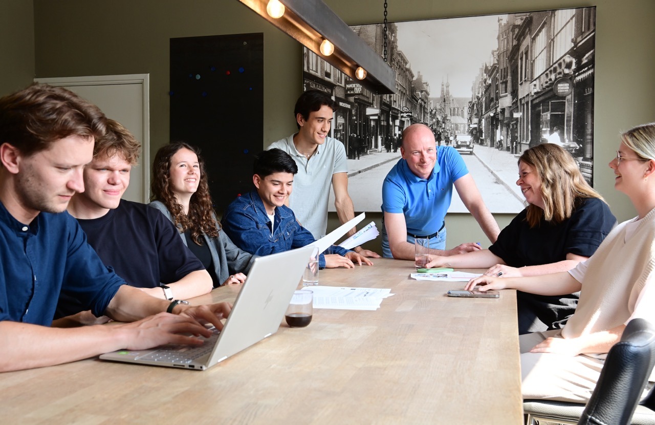 een groep van 8 sea marketing personeel die in overleg zijn rond een grote tafel